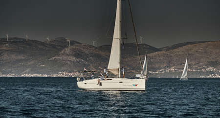 Croatia, Adriatic Sea, 15 September 2019: The race of sailboats, a regatta, reflection of sails on water, Intense competition, bright colors, island with windmills are on backgroundのeditorial素材