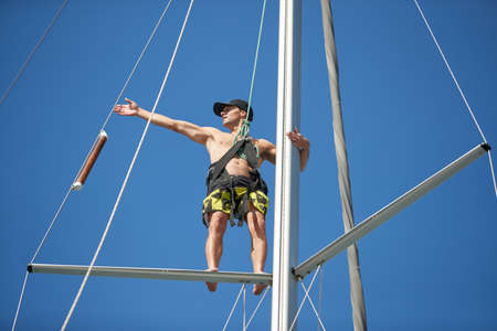 Croatia, Split, 15 September 2019: The sailor costs on the top part of a mast, participant of a sailing regatta with blue sky on a background, people prepare for the forthcoming race, skiperのeditorial素材