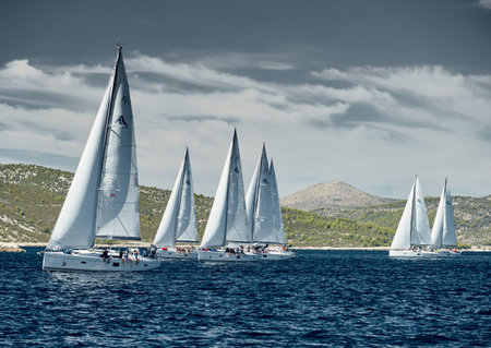 Croatia, Adriatic Sea, 18 September 2019: Sailboats compete in a sail regatta, sailboat race, reflection of sails on water, number of boat is on aft boats, island is on background, clear weatherのeditorial素材