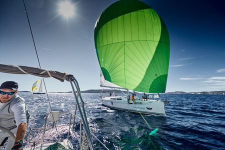 Croatia, Mediterranean Sea, 18 September 2019: The team of sailboat turns off the boat, sailboats compete in a sail regatta, The team works, pulls to a rope, a steering wheel, multicolored spinnakersのeditorial素材