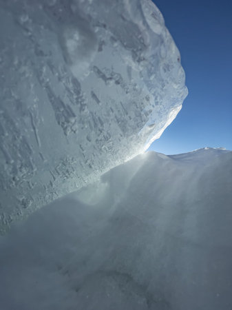 Ice slopes in sunny winter day, transparent ice of blue color, purely blue sky, long shadows, a pure...