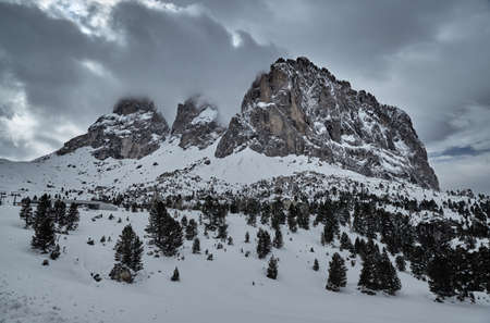 Aerial view of the Dolomites snow-covered mountains in Italy at sunny day, Canazei, ski resort, the twisted road, the blue sky with white clouds, famous place in the worldの写真素材