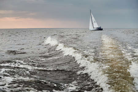 Russia, St.Petersburg, 05 September 2020: The lonely sailboat in a list goes by sea, the sky of pink color, the storm skyのeditorial素材