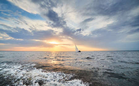 Russia, St.Petersburg, 05 September 2020: The lonely sailboat in a list goes by sea, the sky of pink color, the storm skyのeditorial素材