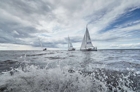 Russia, St. Petersburg, 23 July 2021: Competition of sailboats in regatta at storm weather, race, big waves, sail regatta, cloudy weather, main sail, jib, team work, splashesのeditorial素材
