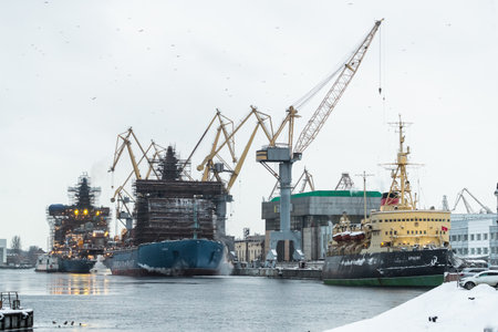 Russia, St. Petersburg, 05 February 2021: The construction of nuclear icebreakers, cranes of of the Baltic shipyard in a frosty winter day, steam over the Neva river, smooth surface of the riverのeditorial素材