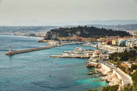 The ferry terminal in port Nice - France at sunny day, A lot o motor boats and luxury yachts are moored in port, mooring ropes go into the amazing azure water, famous embankment and lighthouseの写真素材
