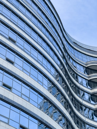 Curved lines of the facade of a large building, reflection of the blue sky in the glass walls,...