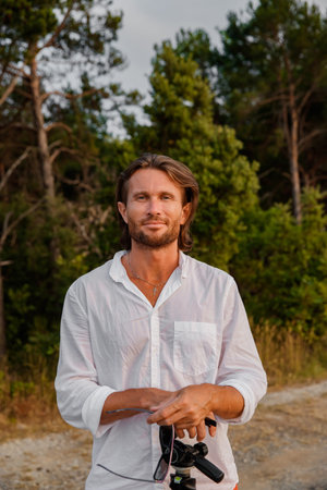 Portrait of handsome brutal man with long hair at sunset, the blue eyes, an easy bristle, he is...