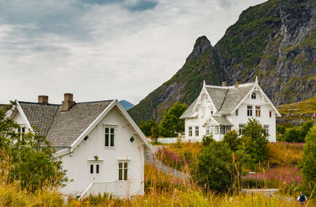 Lofoten Islands, classic norwegian landscape, small houses of white color on the coast, rocky coast with dramatic skyの写真素材