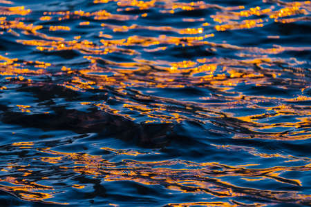 Reflection of orange and deep blue color of river ripple wavesの写真素材