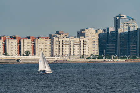 Russia, St. Petersburg, 10 June 2022: The residential complex under construction on the embankment of the Neva River on Vasilievsky island in sunny day, construction cranes, sailing yachtsのeditorial素材