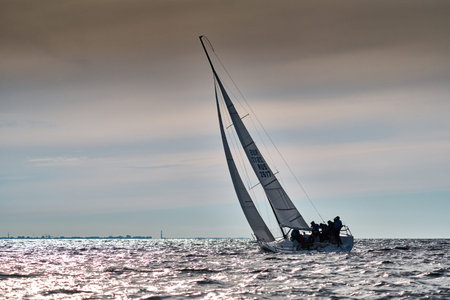 Russia, St. Petersburg, 10 June 2022: Sailboat in sea at sunset, orange sky, sail regatta,...