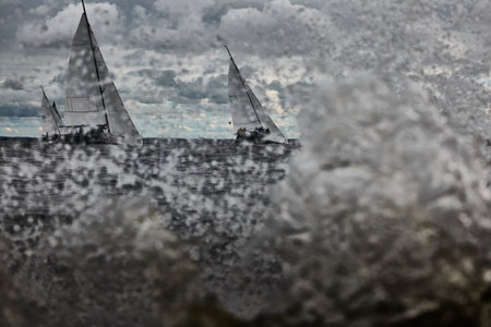 Russia, St. Petersburg, 17 June 2022: Splashes of water in sailing regatta, teamwork in sailing yacht at stormy weather, hot pursuit, clouds skyのeditorial素材