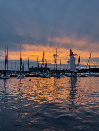 Russia, St. Petersburg, 12 July 2022: The yacht club with piers and sailing boats against the backdrop of the expressway and the football stadium Gazprom Arena at sunset, flags and mastsのeditorial素材