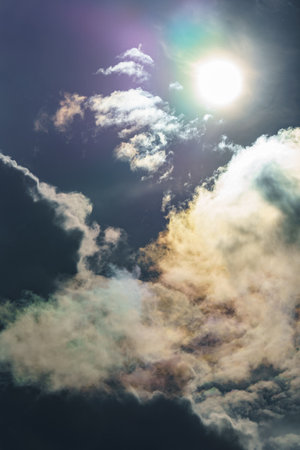 Diffraction of light on drops of supercooled water in clouds, rainbow clouds against the blue sky in clear sunny weather, irisation of cumulus clouds, optical phenomenon, spectral colorsの写真素材