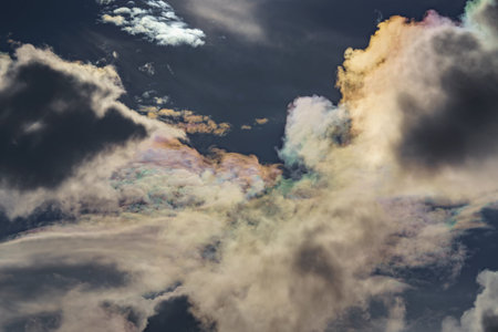 Diffraction of light on drops of supercooled water in clouds, rainbow clouds against the blue sky in...