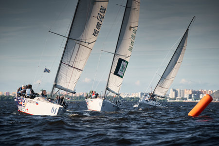 Russia, St.Petersburg, 07 July 2023: The sailing race, few boats in a roll go at high speed, sailing boats are in regatta at sunset, handsome sailors on the board of yacht, wind and splashesのeditorial素材