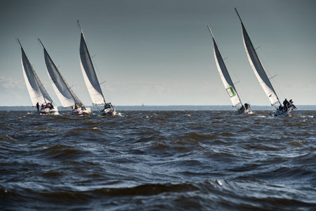 Russia, St.Petersburg, 07 July 2023: The sailing race, few boats in a roll go at high speed, sailing boats are in regatta at sunset, handsome sailors on the board of yacht, wind and splashesのeditorial素材