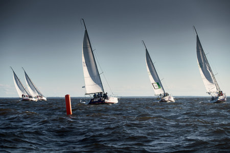 Russia, St.Petersburg, 07 July 2023: The sailing race, few boats in a roll go at high speed, sailing boats are in regatta at sunset, handsome sailors on the board of yacht, wind and splashesのeditorial素材