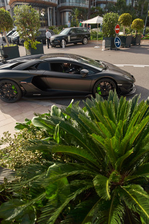 Monaco, Monte-Carlo, 22 October 2022: Square Casino Monte-Carlo at sunset, luxury cars, famous Hotel de Paris, wealth life, tourists take pictures of the landmark, pine trees, flowersのeditorial素材