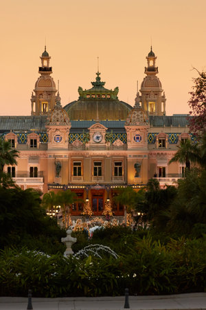 Monaco, Monte-Carlo, 12 November 2022: The famous square of Casino Monte-Carlo is at dusk, attraction night illumination, luxury cars, players, tourists, splashes of fountainのeditorial素材