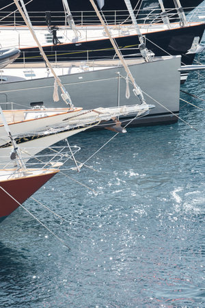 Sun glare on glossy board boats, azure water, tranquillity in port Hercules, bows of moored sailing...