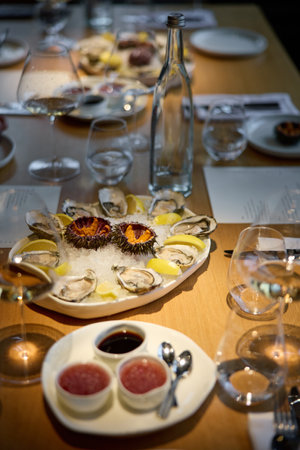 Champagne tasting, Wine glasses are on the table, stylish table setting, sparkling wine bubbles, oysters and sea urchins, special sauceの写真素材