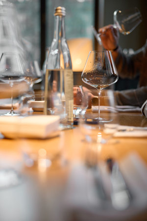 Wine glasses are on the table, stylish table setting, A hand holds a beautiful elegant glass with rose sparkling wine, an intimate light, a plate with oysters and lemonの写真素材