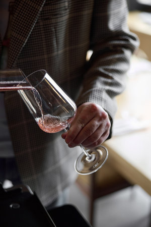 Champagne tasting, The sommelier pours sparkling wine from the decanter into a beautiful glass, Wine glasses are on the table, stylish table setting, sparkling wine bubblesの写真素材