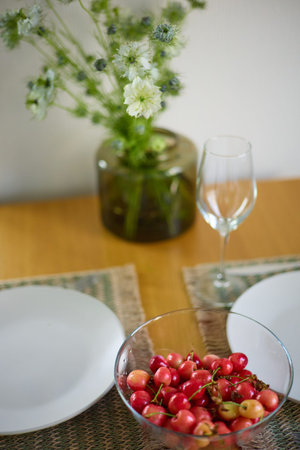 a bouquet of daisies in a glass vase stands on a table on a white background, a wine glass, a wine...