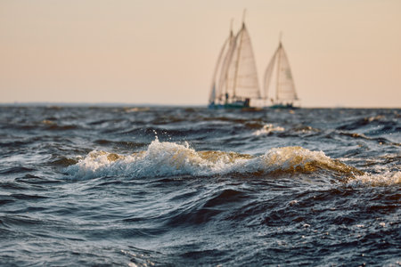 Sailing regatta in the Gulf of Finland at sunset, two sailing yachts competing in a race, splashing water from under the boats, teamwork, board the boatの写真素材