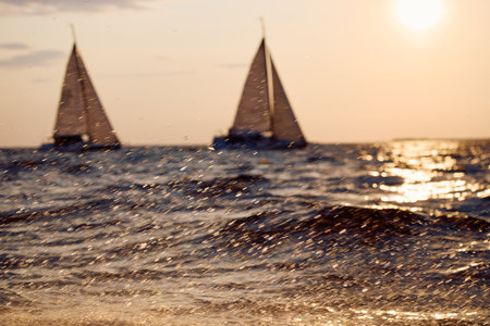 Sailing regatta in the Gulf of Finland at sunset, two sailing yachts competing in a race, splashing water from under the boats, teamwork, board the boatの写真素材