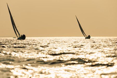 Sailing regatta in the Gulf of Finland at sunset, few sailing yachts competing in a race, splashing water from under the boats, teamworkの写真素材