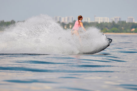 athletic girl rides a jet ski with splashes, she is having fun on a jet ski with splashes in the waters of the Gulf of Finland, Russia, St.Petersburgの写真素材
