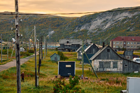 Weathered wooden houses in Teriberka at dusk, Russia, Kola Peninsula, evoke a bygone era, standing as silent witnesses to the passage of time. Teriberkas historical architecture conceptの写真素材