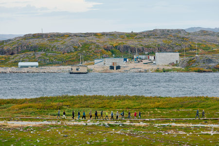 Russia, Teriberka, 13 September 2025: People walk along a wooden path at sunset, the coast of the...