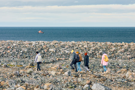 Russia, Teriberka, 13 September 2025: People walk on coast of the Barents Sea at sunset, the rocky...