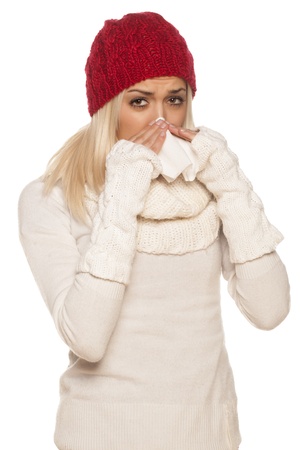 cold girl with a red winter hat wipes his nose with a tissueの写真素材