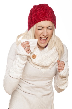 cold girl with a red winter hat sneezed on white backgroundの写真素材
