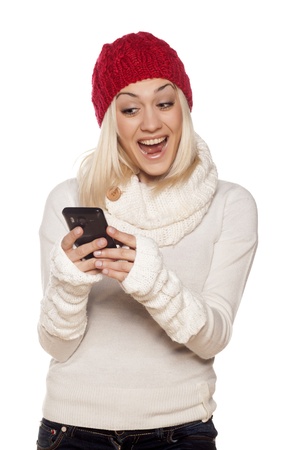 beautiful blonde smiling girl reads the news on her phoneの写真素材