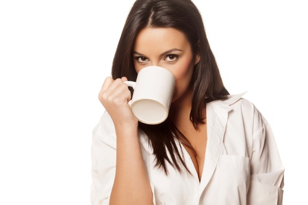 beautiful brunette in a white men s shirt drinking morning teaの写真素材