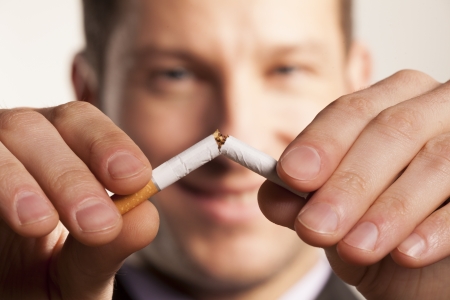 smiling man with a blurred face breaks a cigaretteの写真素材