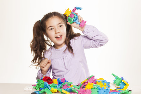 Beautiful little girl enjoys playing with toys on the desk on white backgroundの写真素材