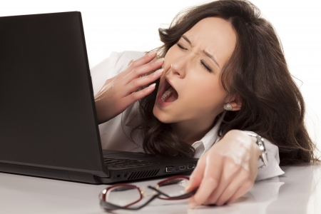 sleepy secretary on her laptop in the workplace on white backgroundの写真素材