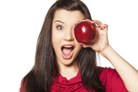 smiling beautiful dark-haired girl with blue eyes showing red appleの写真素材
