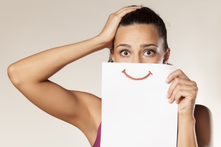 desperate girl with a smile painted on paperの写真素材