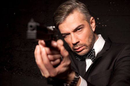 handsome man in a suit aiming with a gun