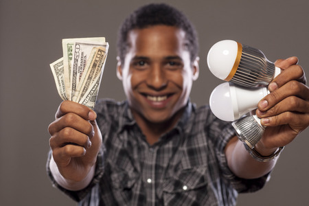 smiling man showing money saved by using LED bulbsの写真素材