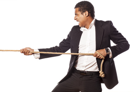 African businessman pulling a rope on white backgroundの写真素材